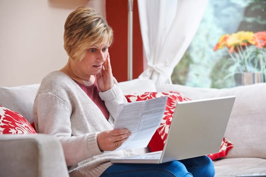 Woman looking happy while sitting at home doing home banking with laptop