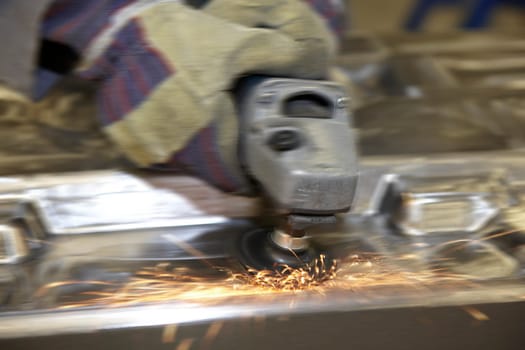 factory floor worker using a angle grinder on metal surface