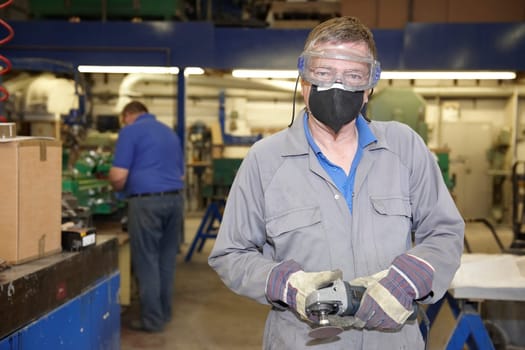 factory floor worker using a angle grinder on metal surface