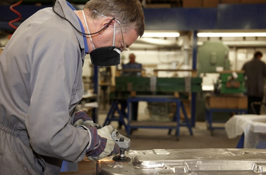 factory floor worker using a angle grinder on metal surface