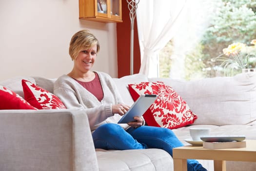 Mother enjoying surfing on the net while relaxing at home with coffee