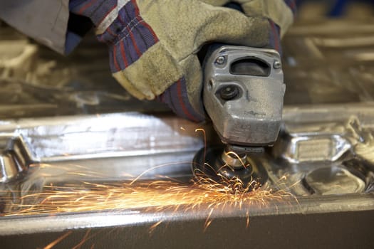 factory floor worker using a angle grinder on metal surface
