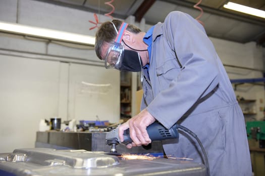 factory floor worker using a angle grinder on metal surface