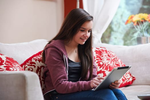 Teenage girl using a tablet pc while sitting at home