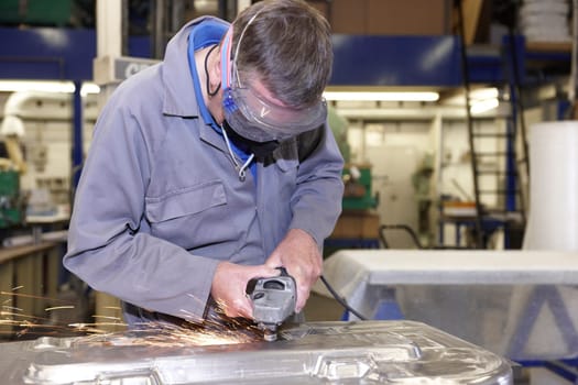 factory floor worker using a angle grinder on metal surface