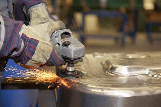 factory floor worker using a angle grinder on metal surface