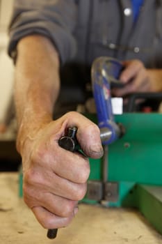 worker on factory floor tightening clamps to secure a machine