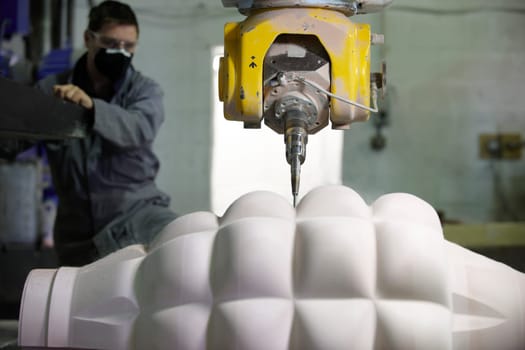 worker controlling a multi axis milling machine