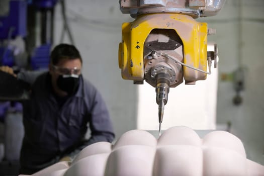 worker controlling a multi axis milling machine