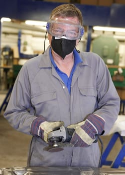 factory floor worker using a angle grinder on metal surface