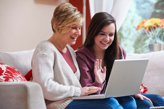 Mother and daughter enjoying surfing on the net while relaxing at home with coffee