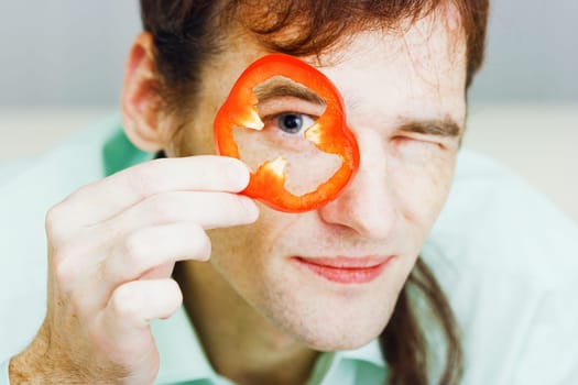 Young man with red pepper. Face close-up. humor