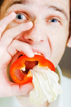 Young man with red pepper. Face close-up. humor