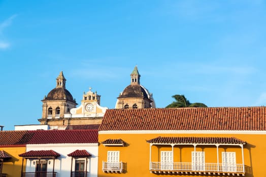 Early morning view of the facades of historic colonial buildings with a church behind them in the center of Cartagena, Colombia