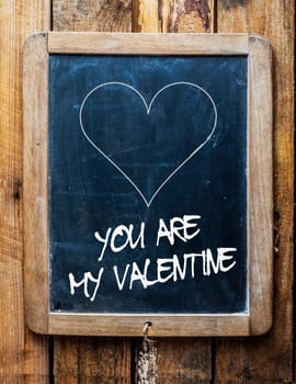Valentines message on an old retro school slate in a rustic weathered wooden frame saying - You are my Valentine - under a simple hand drawn outline of a heart for a heartfelt tender greeting