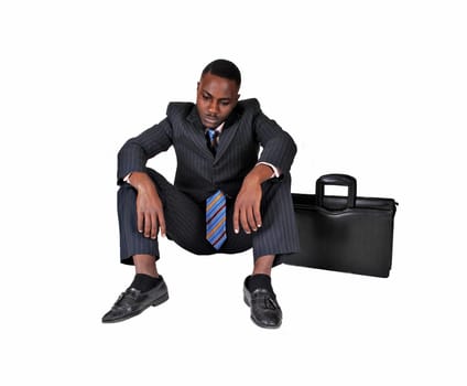 A black businessman sitting on the floor with briefcase on his side.very disappointed, over white background..
