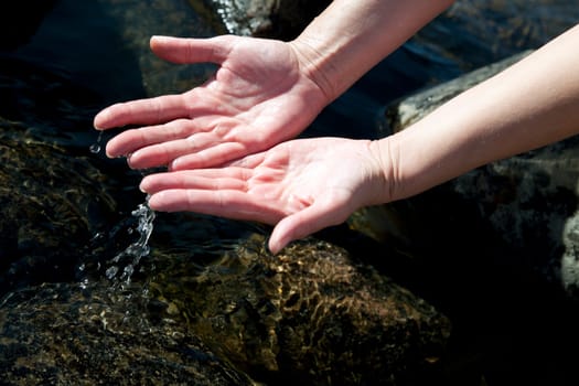 Woman hands playing with natural water