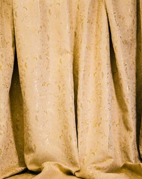 Hanging drapes of gold damask with a luxurious pattern of shiny acanthus leaves for an elegant interior decor