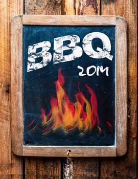 Rustic advertisement for a BBQ on a vintage kids school slate with a picture of red hot flames and an annotation at the bottom saying - Mans stuff