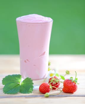 Tall glass of delicious strawberry smoothie blended with yoghurt or ice cream and fresh organic berries for a healthy drink full of vitamins and antioxidants