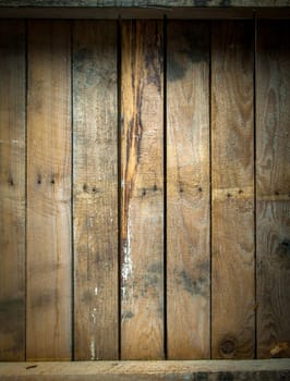Background texture of a grungy stained and weathered wooden table top with a line of old nails and parallel vertical planks