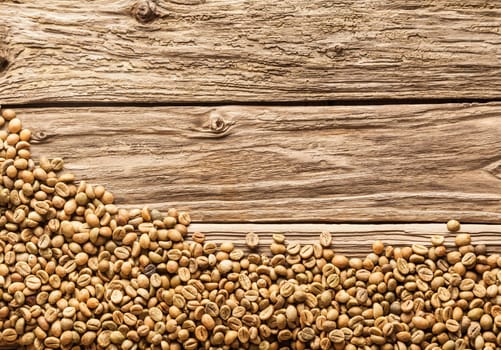 Coffee bean border with raw brown fresh dried beans arranged along the bottom of the frame on weathered rough textured rustic wood with copyspace