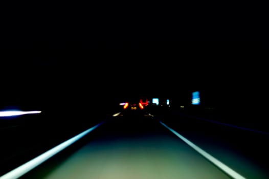 The photograph of a night drive on the highway. Lights blur due to speed.
