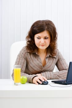 Young woman in office looks at a glass of juice