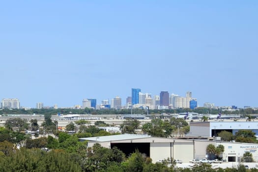 FORT LAUDERDALE, FLORIDA - MARCH 30, 2013: A commercial plane landing at Fort Lauderdale-Hollywoood International airport in front of a background of downtown Fort Lauderdale on a sunny winter day.
