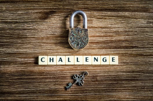 Old vintage padlock and key on wooden texture with challenge sign