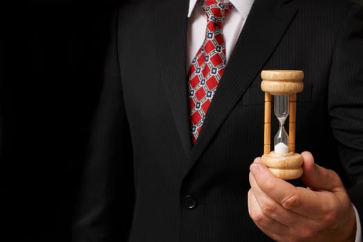 businessman holding hourglass towards camera with space for copy