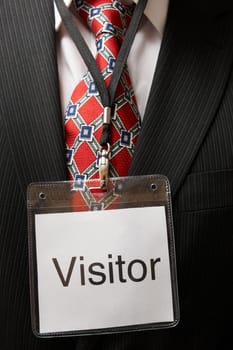businessman wearing a visitor identification badge around his neck