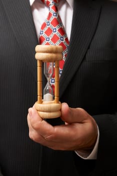 businessman holding hourglass towards camera with space for copy