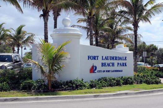 FORT LAUDERDALE, FLORIDA - APRIL 6, 2013: Closeup of Ft Lauderdale Beach Park sign with palm trees and autos in the background. Location is at 1100 Seabreeze Boulevard and is open 5 AM to midnight.