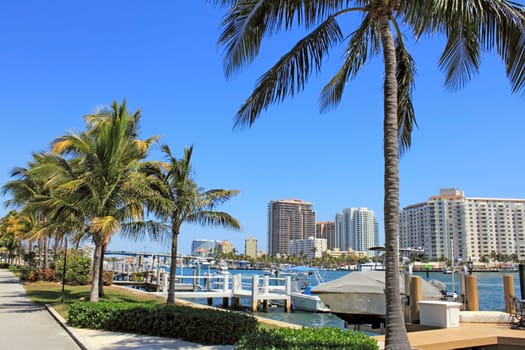 FORT LAUDERDALE, FLORIDA - MARCH 30, 2013: Beautiful view of boats on the Atlantic Intracoastal with modern buildings lining it’s banks along with tropical palm trees and foliage on a sunny day.