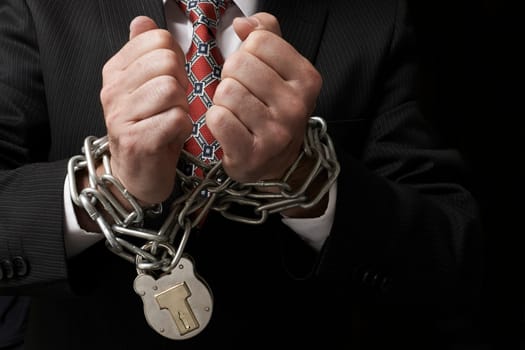 Close up of businessmans hands tied in heavy chains with padlock
