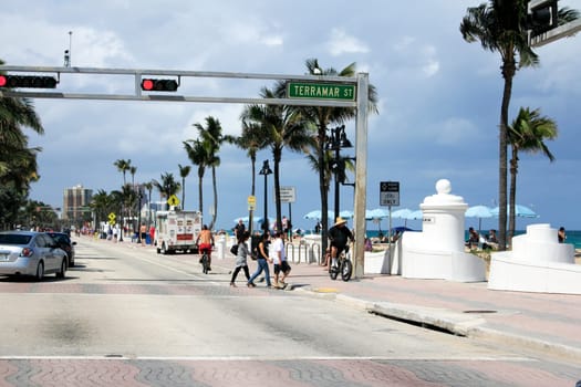 FORT LAUDERDALE, FLORIDA - APRIL 6, 2013: Many people walking, biking and enjoying the Atlantic beach coast on a partly sunny day in tropical south Florida near Terramar Street and State Road A1A.