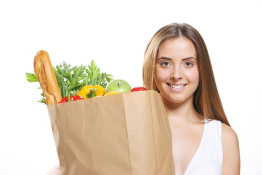 Portrait of smiling young woman holding a shopping bag full of groceries on white background