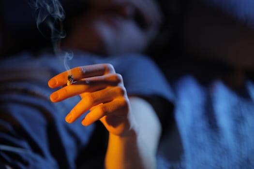 Close up of teenage boy smoking drugs lying on the couch, copy space