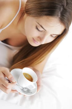Beautiful young woman in bed drinking cofee in the morning.