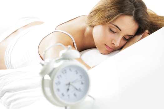 A young lady sleeping on the background with a clock on the foreground.
