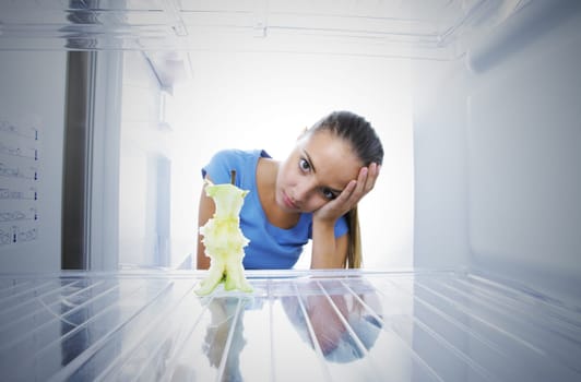 Young woman unhappy to see the empty fridge