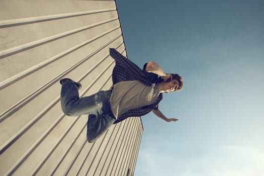 Young man is falling from a building and calling with cell phone
