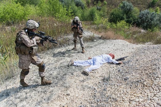 Two US marines making a search of killed muslim warrior