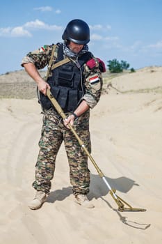 iraqi soldier in the desert with army metal detector