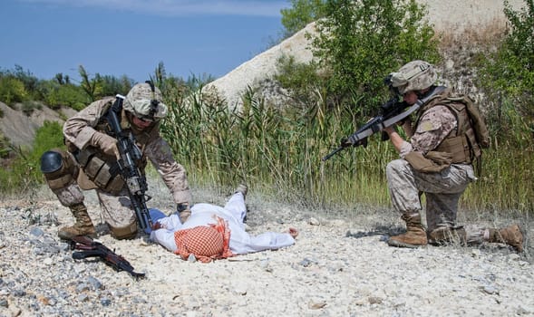 Two US marines making a search of killed muslim warrior