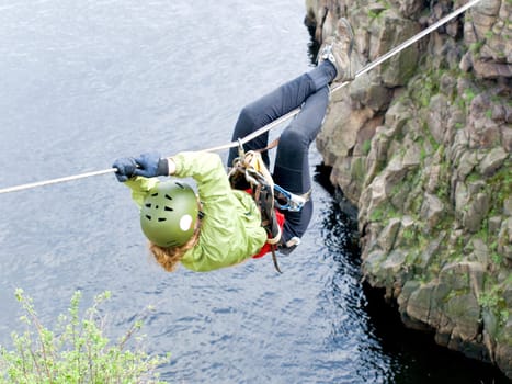 A female climber crosses a gorge along a tyrolean traverse