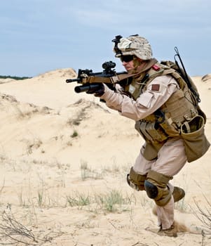 US soldier runs through the desert shooting a gun with grenade launcher