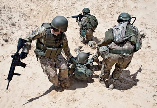 Squad of soldiers evacuate the injured fellow in arms in the desert