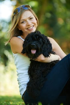 woman relaxing with black dog while on a walk in the park